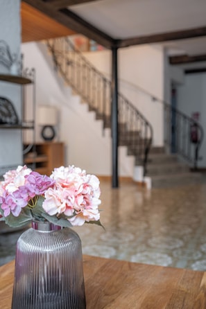 A modern interior with a wooden table, a vase with flowers, a staircase, and a railing.