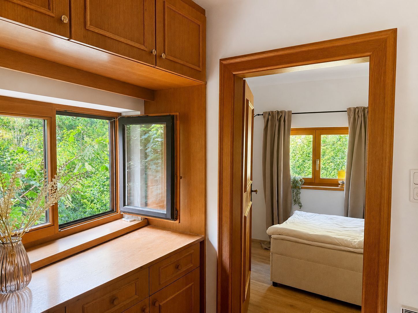 Une chambre avec un lit, une fenêtre avec des rideaux et une vue sur la verdure.