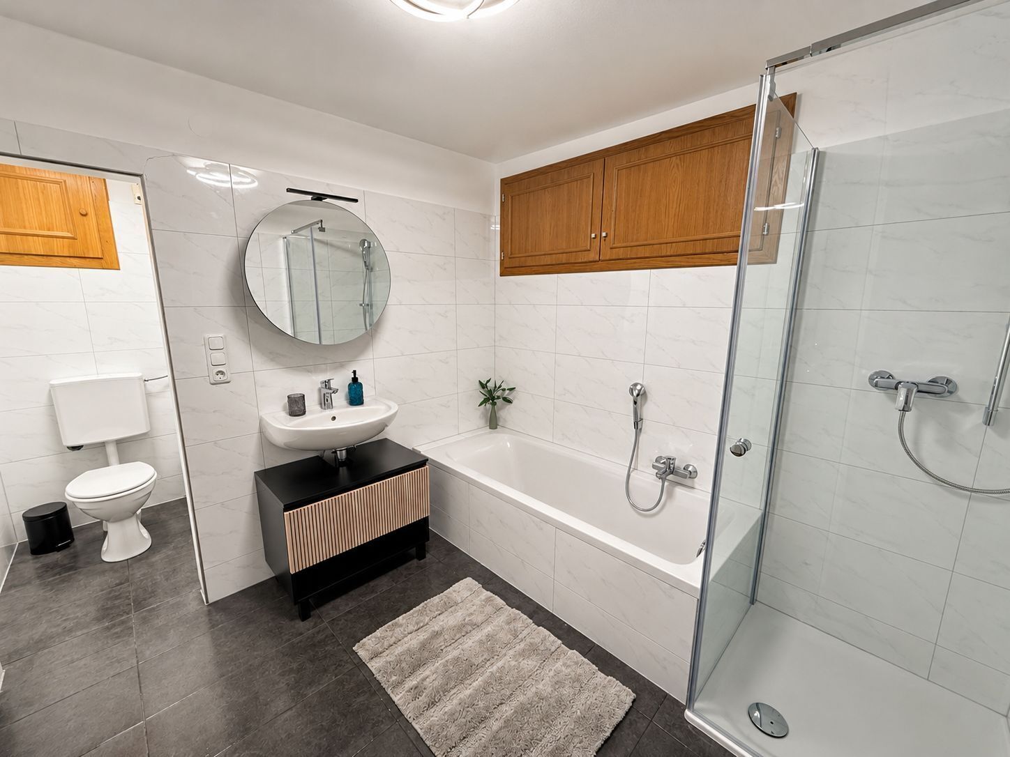 A modern bathroom with a toilet, sink, mirror, and shower.