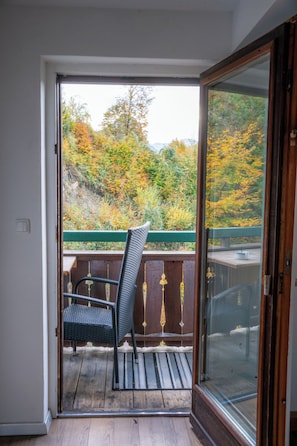 A room with a sliding glass door leading to a balcony with a chair and a table. - Haus Dittelbach (Ried)