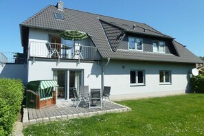 A two-story house with a balcony, a covered outdoor seating area, and a satellite dish. - with garden and terrace (Glowe)