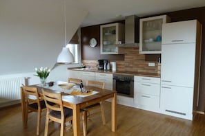 Eine moderne Küche mit weißen Schränken, einem Holztisch und einer Uhr an der Wand.