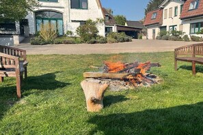 A fire pit in a grassy area with benches and a house in the background. - Holiday apartment with 3 bedrooms (Waldeck)
