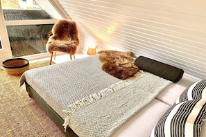 Ein Schlafzimmer mit einem Bett, einem Sessel, einer Lampe und einem Fenster.