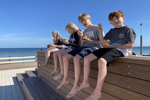 Eine Holzterrasse mit Stufen zu einer Sitzgelegenheit mit Blick auf den Ozean.
