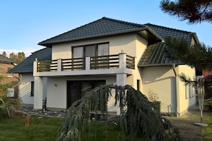 A modern two-story house with a balcony, a paved driveway, and a well-maintained lawn. - Sweet child with terrace (Glowe)