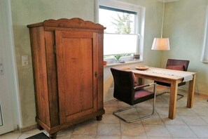 A dining area with a wooden table, a metal chair, a cabinet, and a window with a view. - Sweet child with terrace (Glowe)