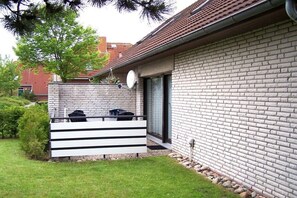 Ein Ziegelhaus mit Terrasse, Satellitenschüssel und Fenster.