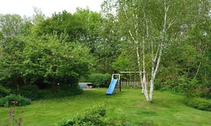 Ein Garten mit Rutsche, üppiger Bepflanzung und Holzzaun.