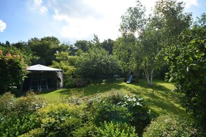 Ein üppiger Garten mit einem Pavillon, einer Rutsche und dichtem Grün.