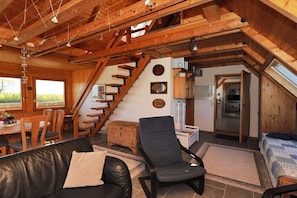 Ein Holzinnenraum mit Treppe, Essbereich, Sofa und Bett.