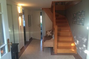 Eine Treppe führt zu einer zweiten Etage, eine Bank mit Kissen und eine Tür mit einer Lampe.