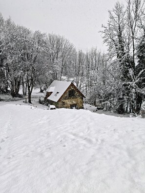 A snow-covered cabin surrounded by trees. - Cozy studio on the first floor of a mountain barn (Ercé)