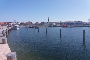 Eine Hafenpromenade mit einem Leuchtturm, einem Boot und Gebäuden im Hintergrund.