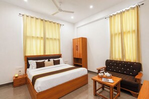 A hotel room with a bed, a sofa, a table with a teapot, and a wardrobe. - Hiara Crystal 5BHK Villa with Pool (Udaipur)