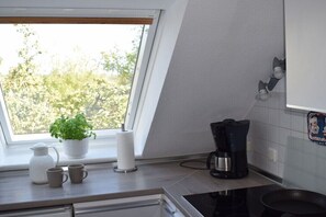 Ett kök med ett fönster, en kaffebryggare och en krukväxt.