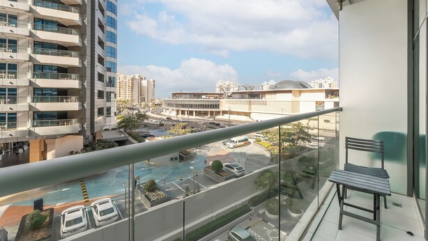 A high-rise building with multiple balconies, a parking area, and a view of the surrounding urban landscape. - Modern studio in Seven Palm, pool and beach (Dubai)