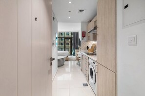 Eine moderne Küche mit Waschmaschine, eine Essecke mit Tisch und Stühlen sowie ein Schlafzimmer mit Bett und Vorhängen.