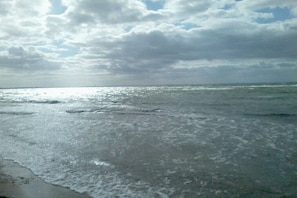 Uma praia com ondas e céu nublado.