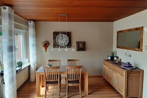 Ein Essbereich mit Holztisch und Stühlen, einer Wanduhr und einem Holzschrank mit Spiegel.