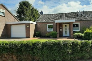 Ein zweistöckiges Backsteinhhaus mit Garage, Eingangstür und Satellitenschüssel.