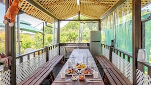 An outdoor dining area with a long table, benches, and a grill.