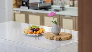 A kitchen counter with a fruit platter, a vase with a flower, and a wooden cutting board. - Jangmi Pension, Daebudo (Incheon)