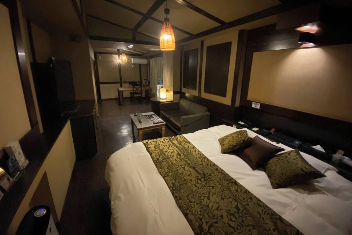A hotel room with a bed, a desk, a chair, a sofa, a TV, and a bathroom.