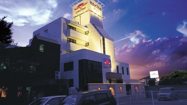 A hotel with a prominent sign, a parking lot, and a fenced area. - HOTEL CACHE - Adults only  (Himeji)