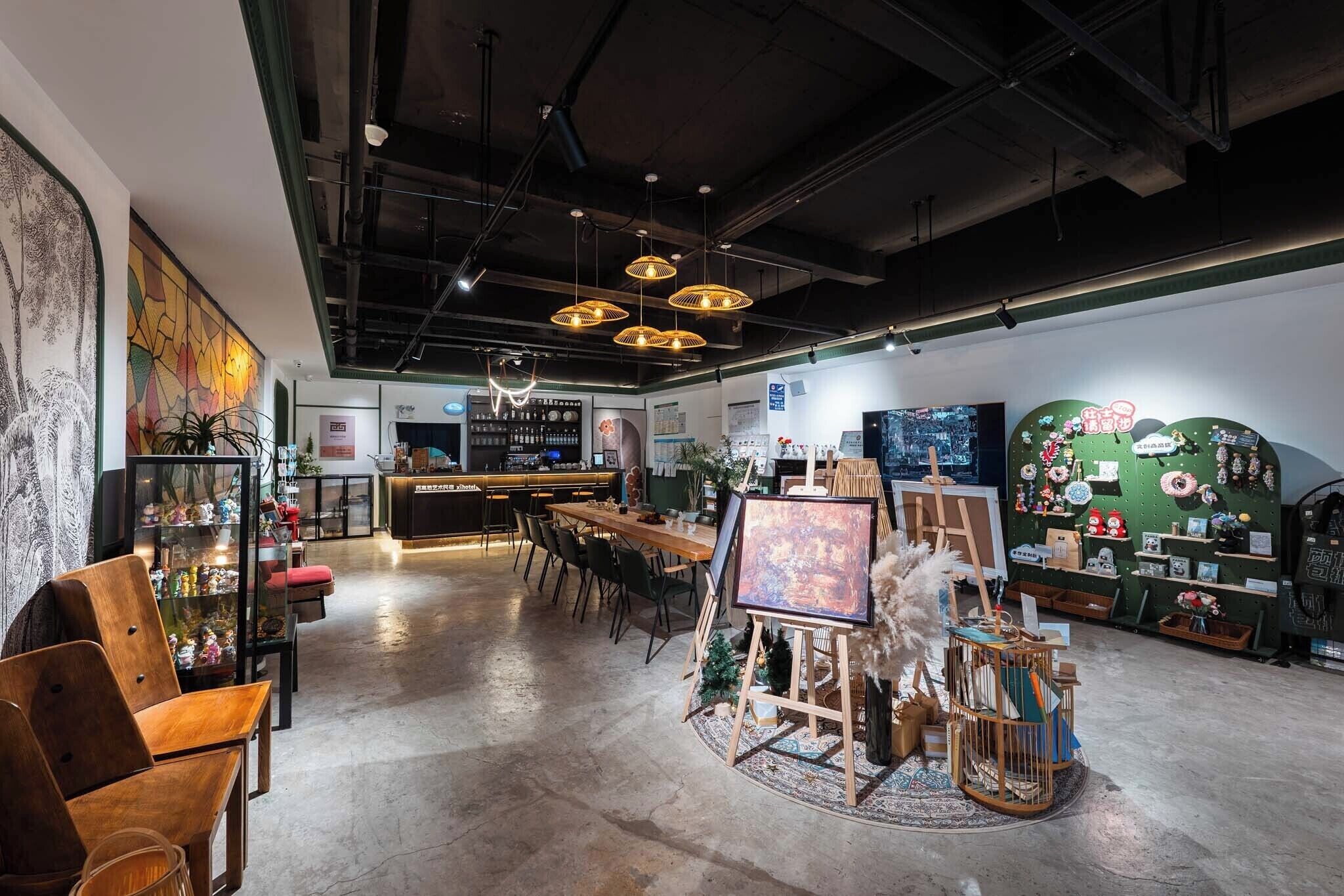 Un interior espacioso con una zona de bar, mesas de comedor y una exhibición de pinturas y objetos decorativos.