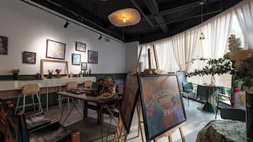 A room with a dining area, a painting on easels, and artwork on the walls.