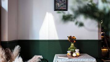 A table with a vase of flowers, a candle, and a small clock, set against a wall with a framed picture.