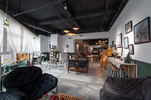 An art gallery with paintings on the walls, a dining area with a long table, and a black leather couch. - Xigaodi Art Homestay Hotel  (Guiyang)
