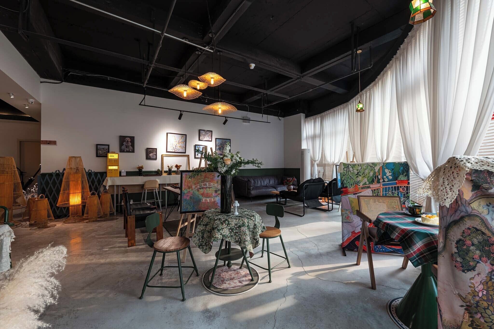 An interior with a dining area, a sofa, artwork, and a table with a floral tablecloth.