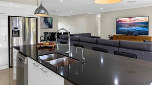 Una cocina moderna con una isla central, electrodomésticos de acero inoxidable e iluminación colgante.