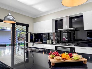 Een moderne keuken met een centraal eiland, roestvrijstalen apparatuur en een verscheidenheid aan fruit en kazen op het eiland.