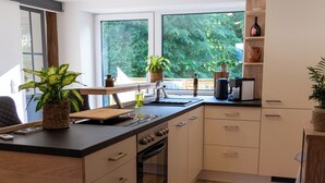 Ett modernt kök med en central köksö, träinredning och stora fönster.