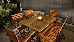 An outdoor patio with a wooden table and chairs, string lights, and a wooden fence. - Apartment 'Wohlfühlappartement Sonnenhalde' with Private Terrace, Garden & Wi-Fi (Sigmarszell)
