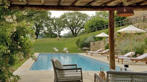 Zona de piscina al aire libre con sillas de descanso y una pérgola.