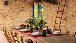 Una mesa de comedor rústica dispuesta con platos, vasos y un florero con flores.