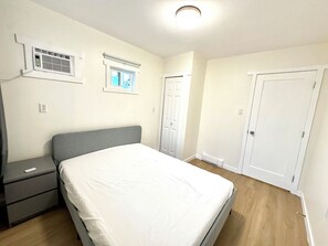 Une chambre Ă coucher comprenant un lit, une table de chevet, une armoire et un appareil de climatisation.