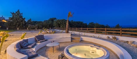 A circular outdoor hot tub area with seating and a small table.