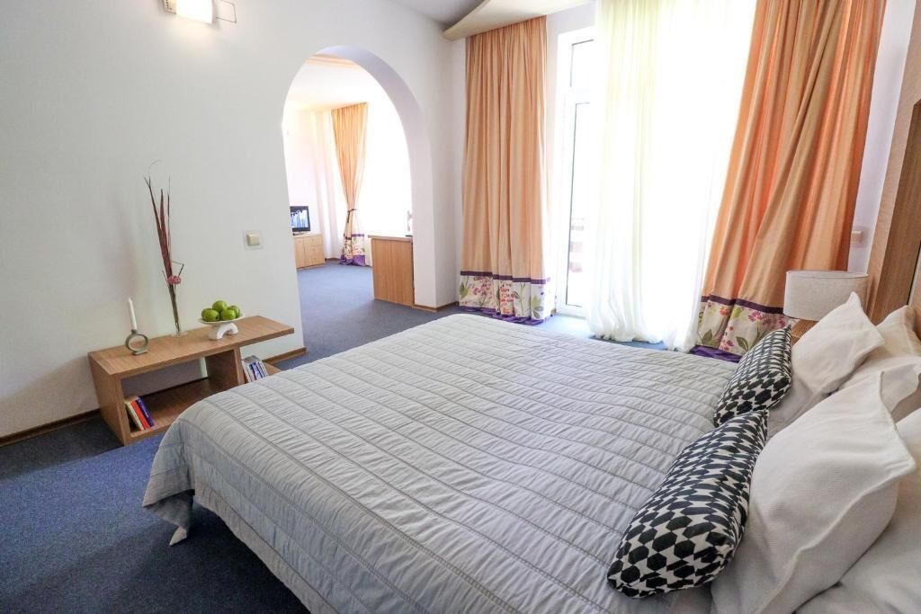 Hotelkamer met een groot bed, nachtkastje, lamp en uitzicht op de gang.