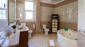 Et badeværelse med vask, toilet, badekar og et vindue.