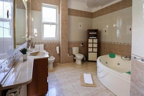 Een badkamer met een wastafel, toilet, badkuip en een raam.
