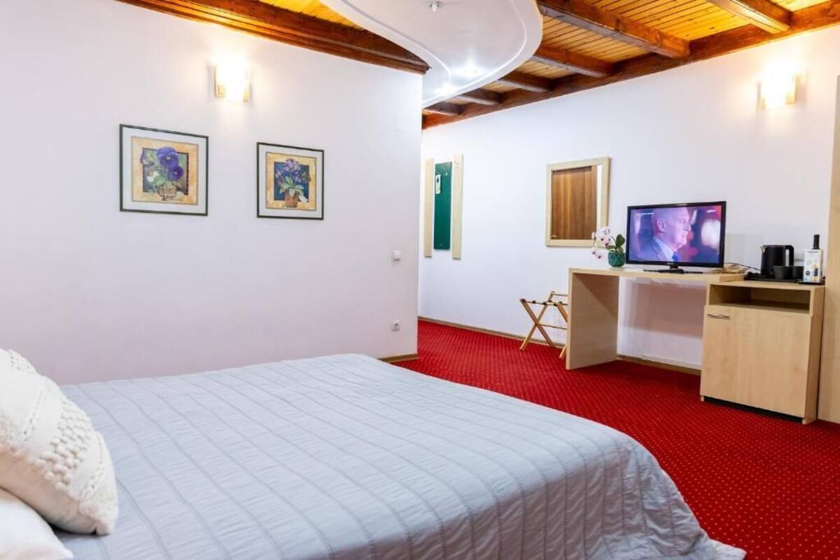 A bedroom with a bed, a desk, a television, and artwork on the walls.