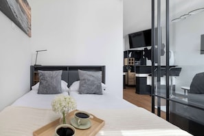Ein modernes Hotelzimmer mit einem Bett, einer Kaffeemaschine und einem Fernseher im Hintergrund.