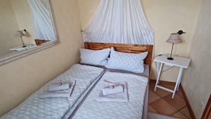Ein Zimmer mit einem Bett, einem Nachttisch, einer Lampe, einem Spiegel und einem Baldachin.