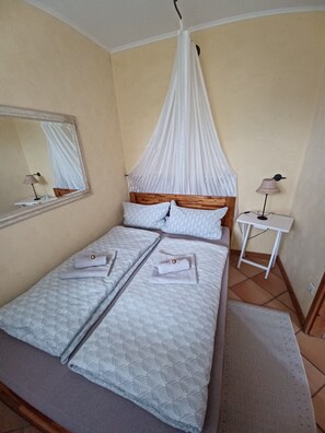 A room with a bed, a bedside table, a lamp, a mirror, and a canopy.