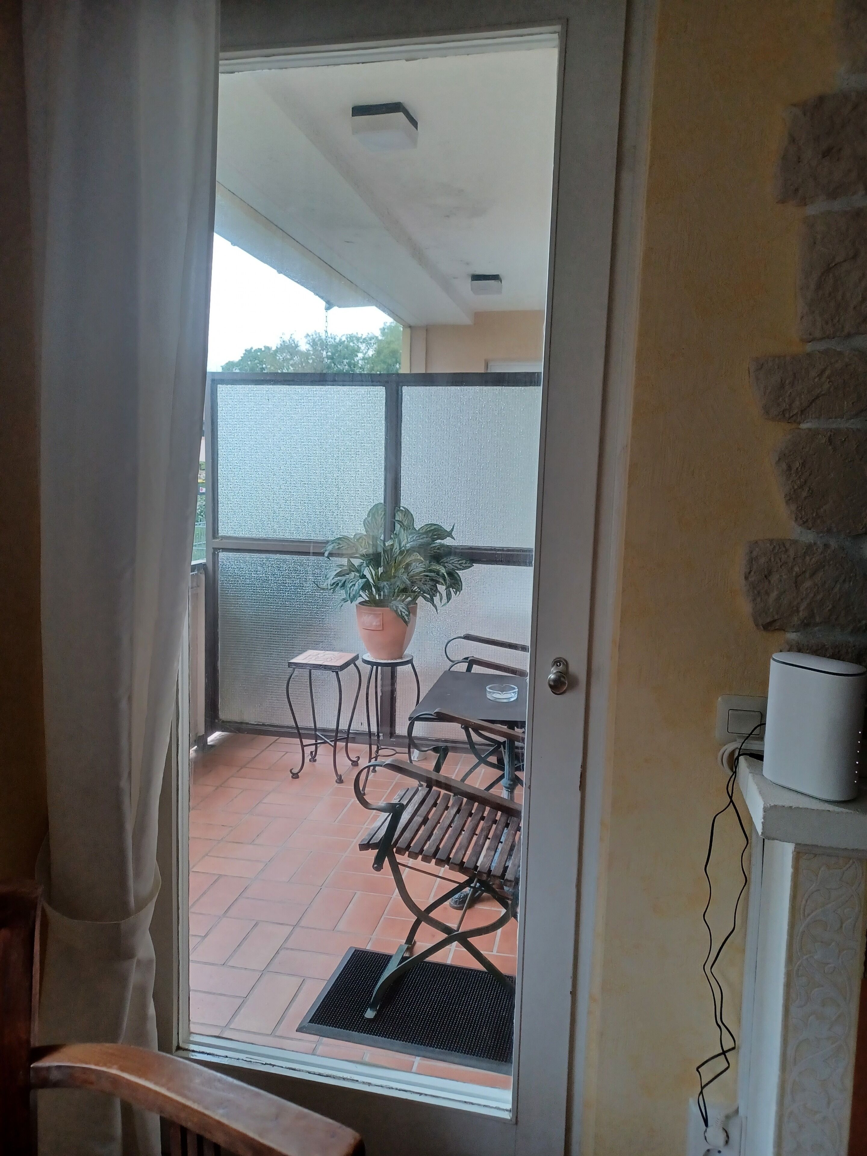 A room with a sliding glass door leading to an outdoor patio with a table, chairs, and a potted plant.